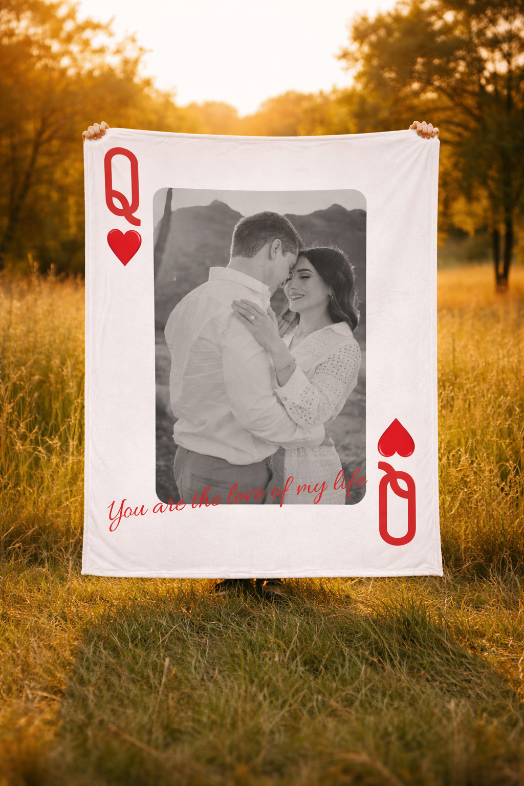 Person holding a large playing card with a photo of a couple and romantic text in a field.