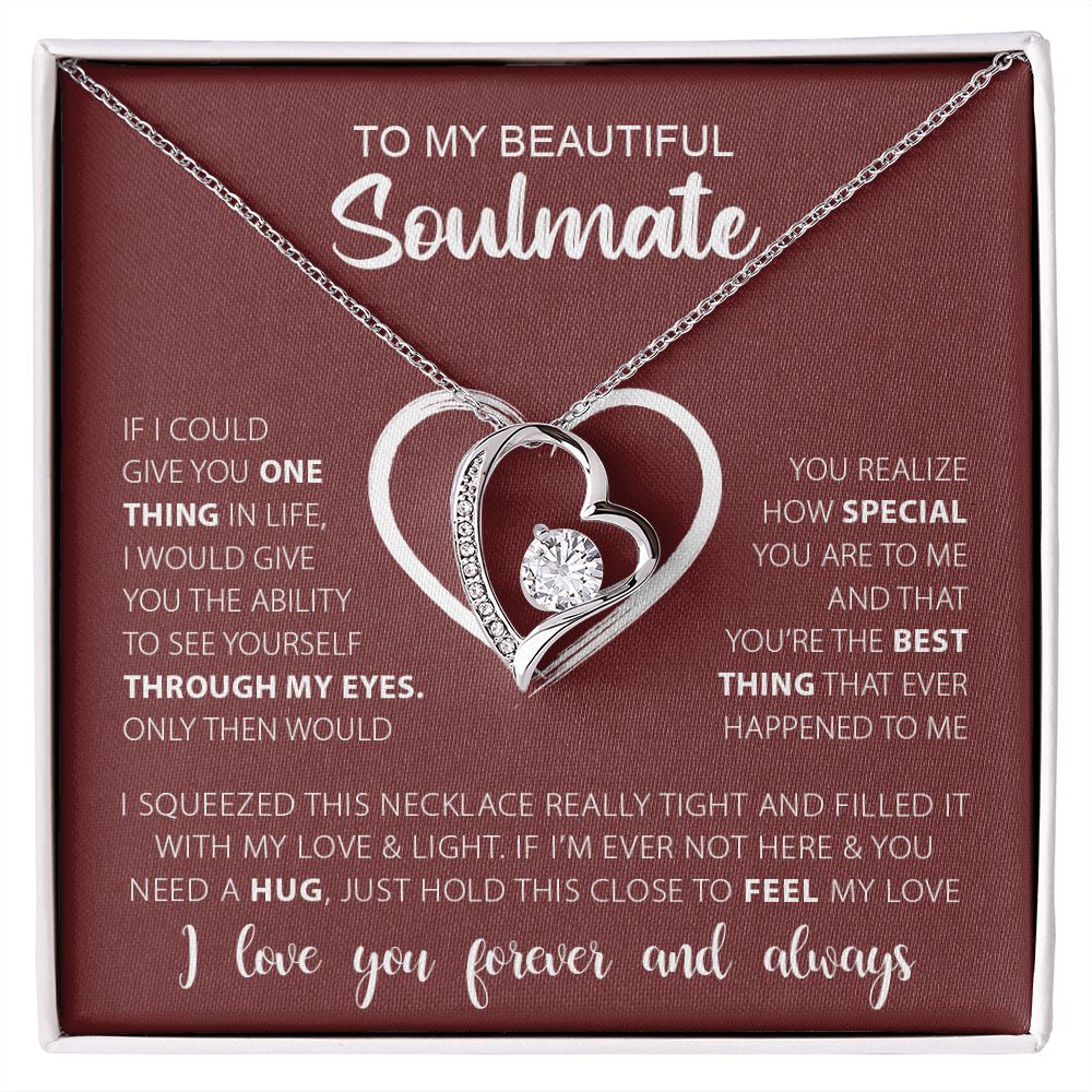 A silver necklace with a heart-shaped pendant featuring a diamond ring, surrounded by smaller crystals. The text on the necklace reads 'To My Beautiful Soulmate'.